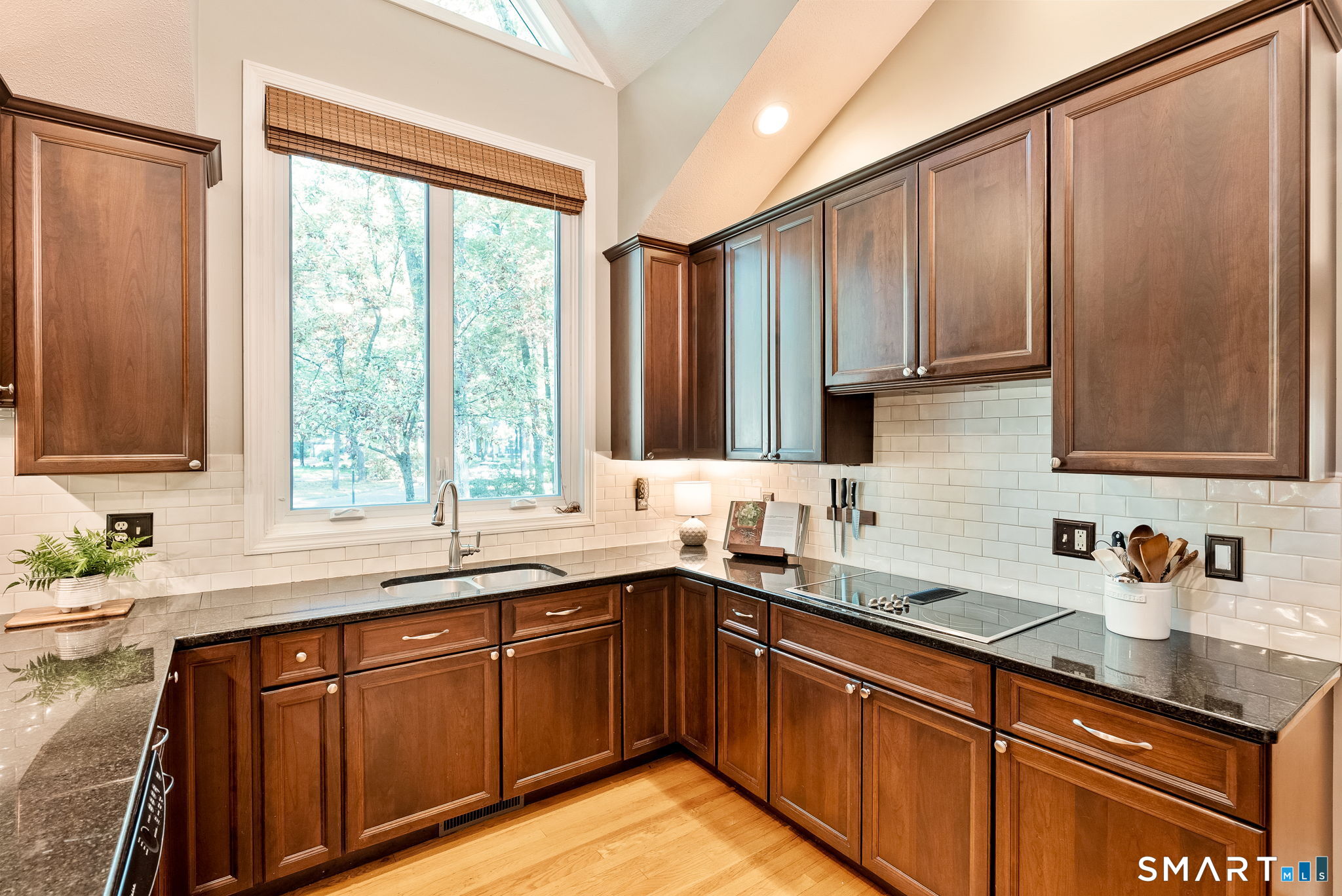 Kitchen with dark wood cabinets, granite counters, and a large window above the sink.