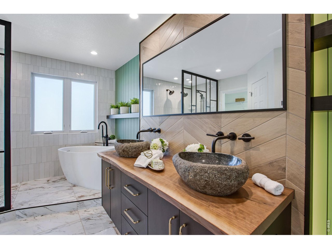 Bathroom with a freestanding tub, double stone vessel sinks, and a black-framed glass shower.