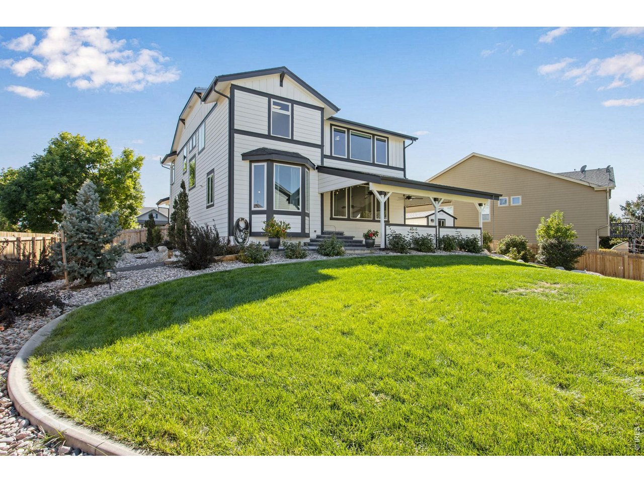 Two-story house with a covered patio and landscaped backyard lawn.