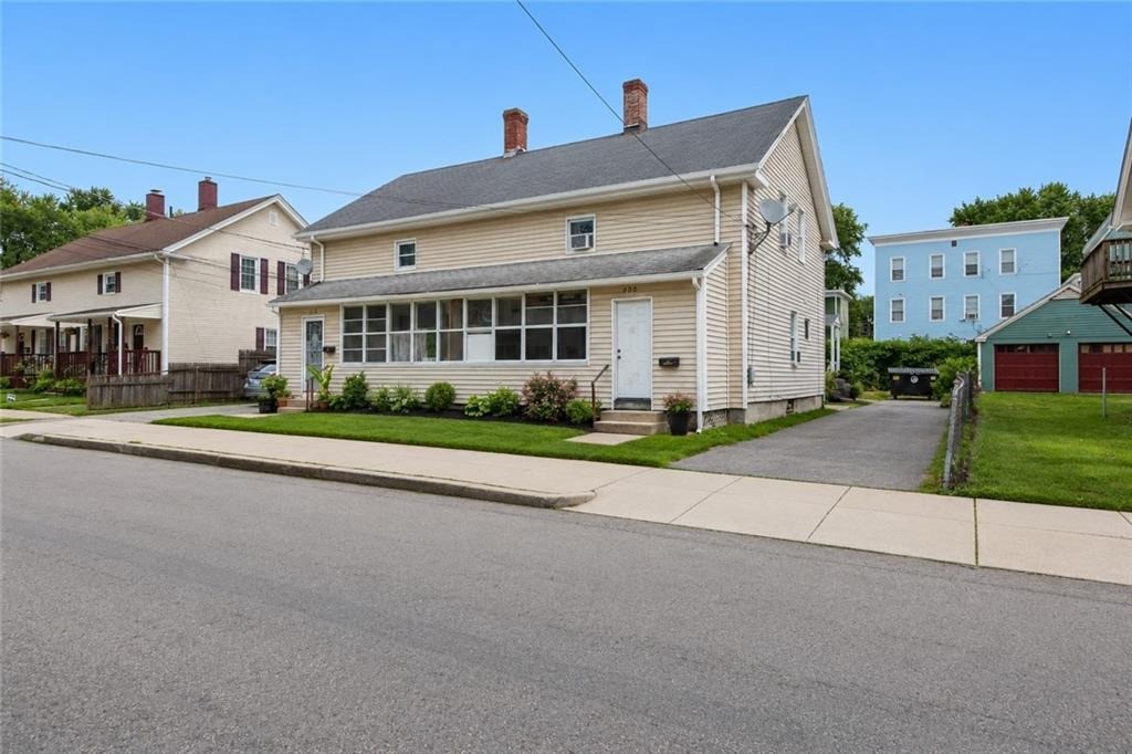 Beige two-story house with an enclosed front porch and driveway beside it.