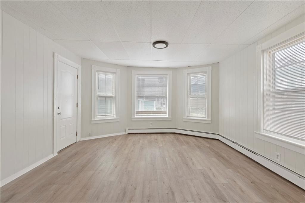 Vacant room with bay windows, pale walls, and light wood flooring.