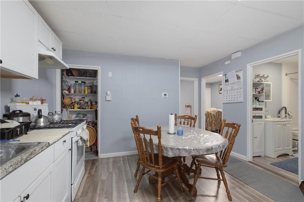 Kitchen and dining area with white cabinets, a round table, and an open pantry.