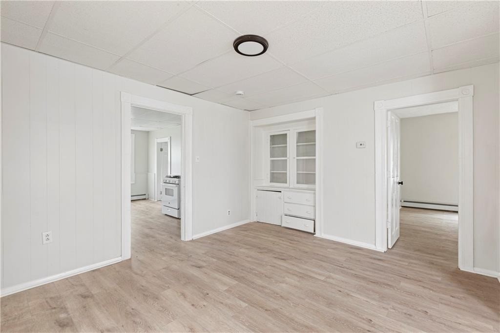 Vacant room with light wood-look flooring and a built-in glass-front cabinet.