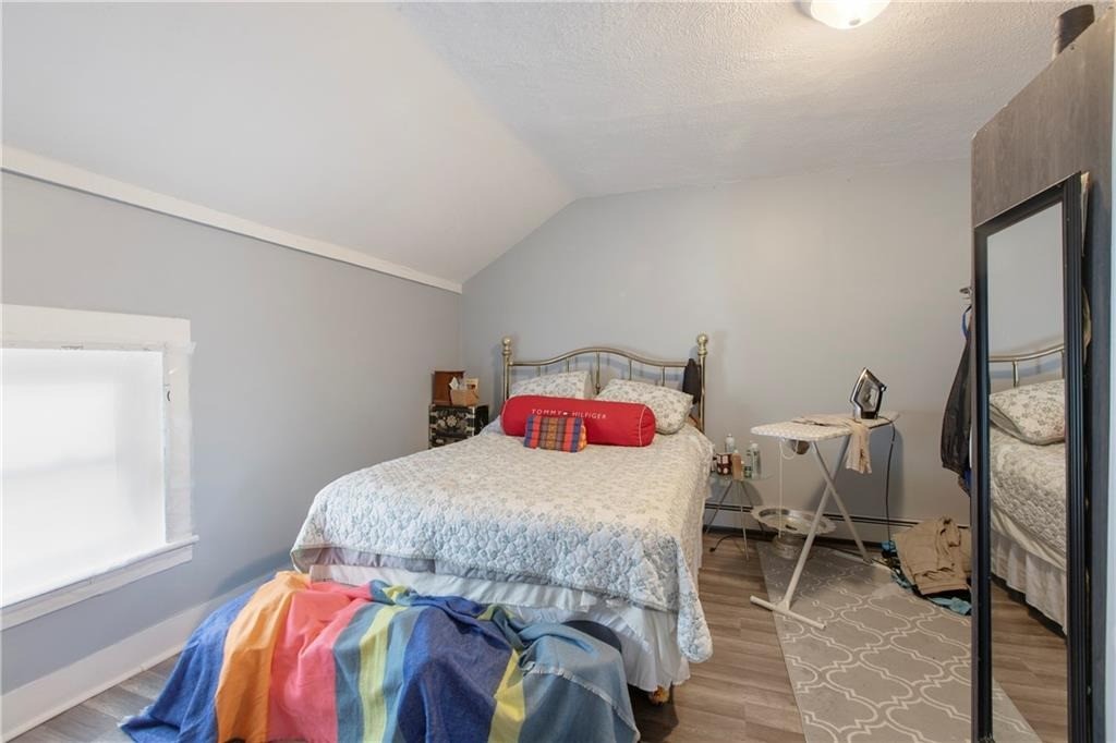 Bedroom with a metal-frame bed, colorful blanket, mirrored wardrobe, and ironing board.