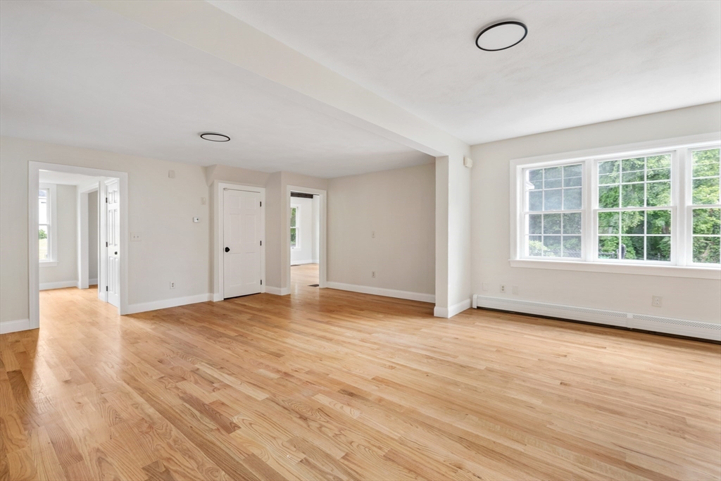 Empty living room with hardwood floors and large multi-pane windows.