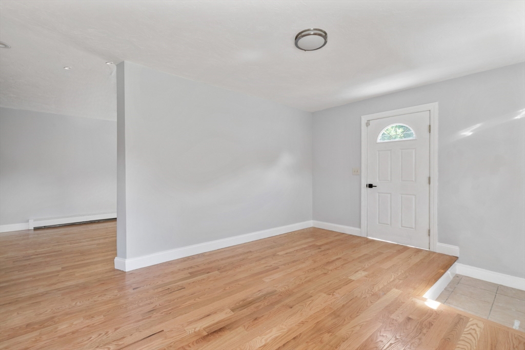 Empty entry area with light wood floors and a white front door with a semicircular window.