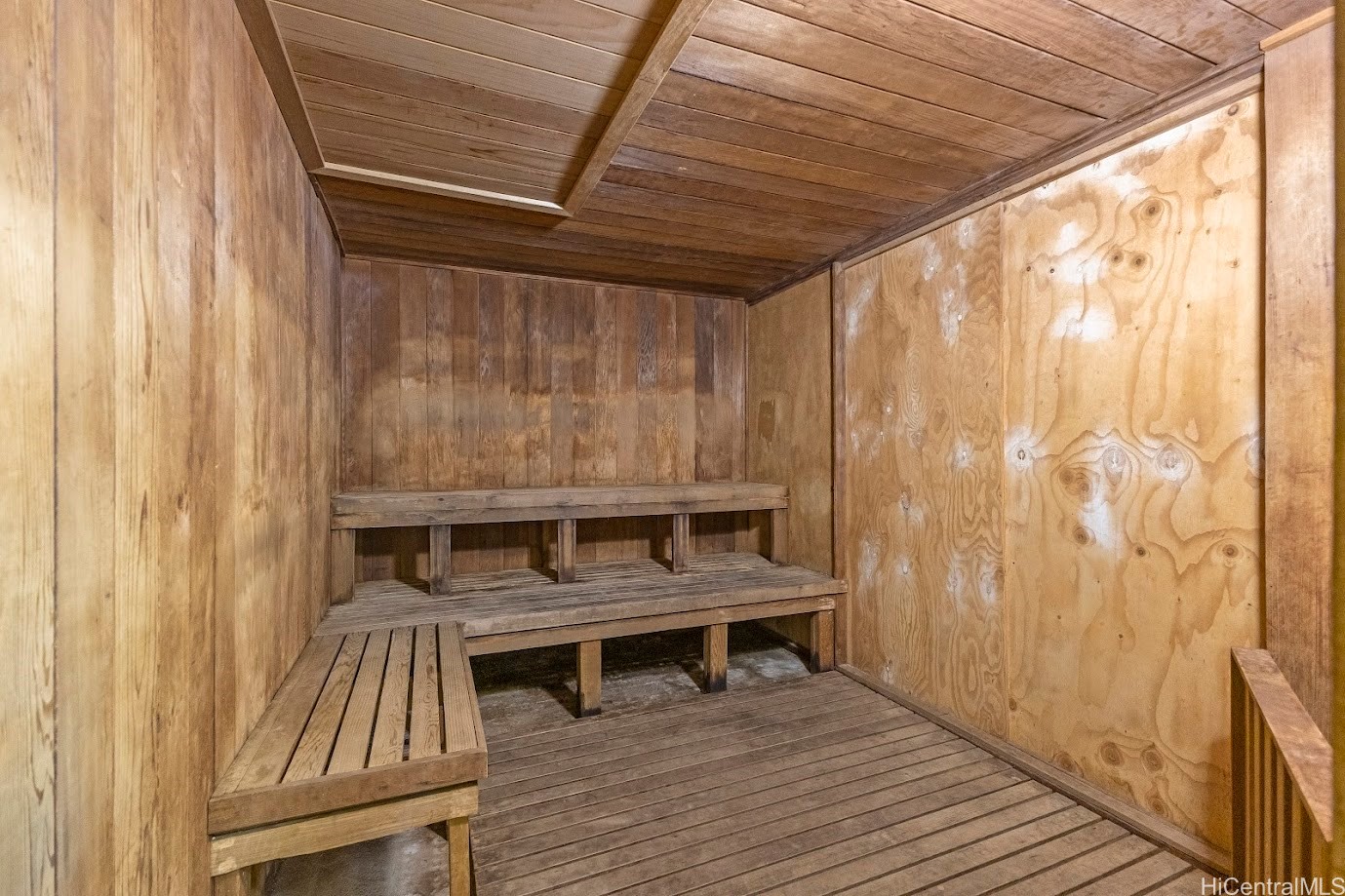 Wood-paneled sauna with tiered built-in benches and a slatted wooden ceiling.