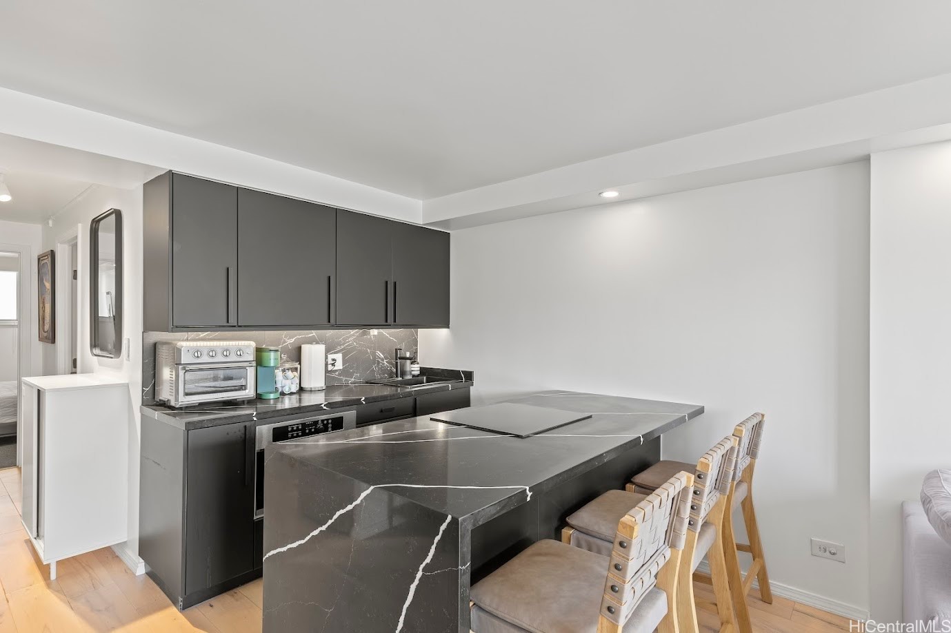 Modern kitchen with dark cabinets, a veined stone island, and upholstered bar stools.