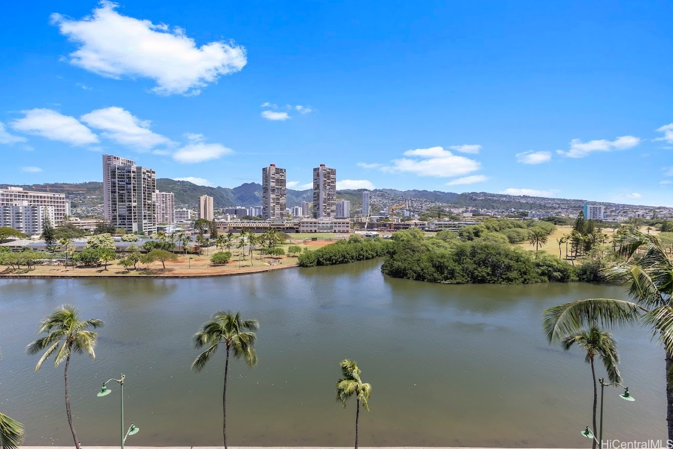 View over the Ala Wai Canal toward Honolulu high-rises and green mountains.