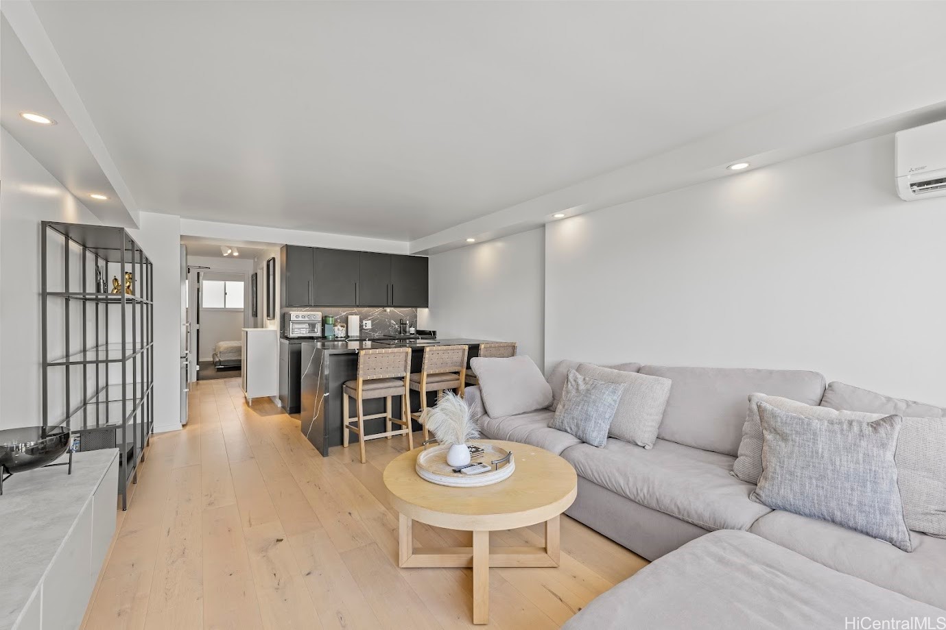 Living room with a large sectional sofa, round coffee table, and open kitchen with bar seating.