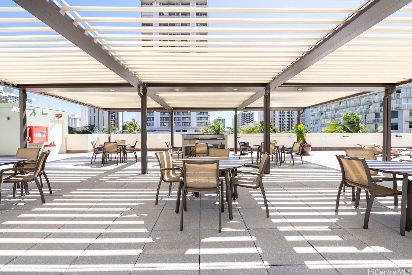 Furnished rooftop terrace with dining tables beneath a slatted pergola.