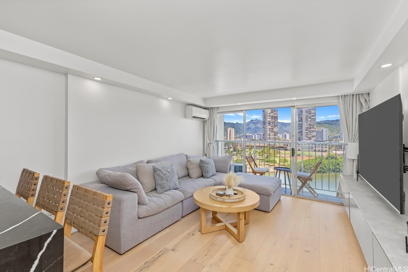 Living room with gray sectional and balcony views of mountains and canal.