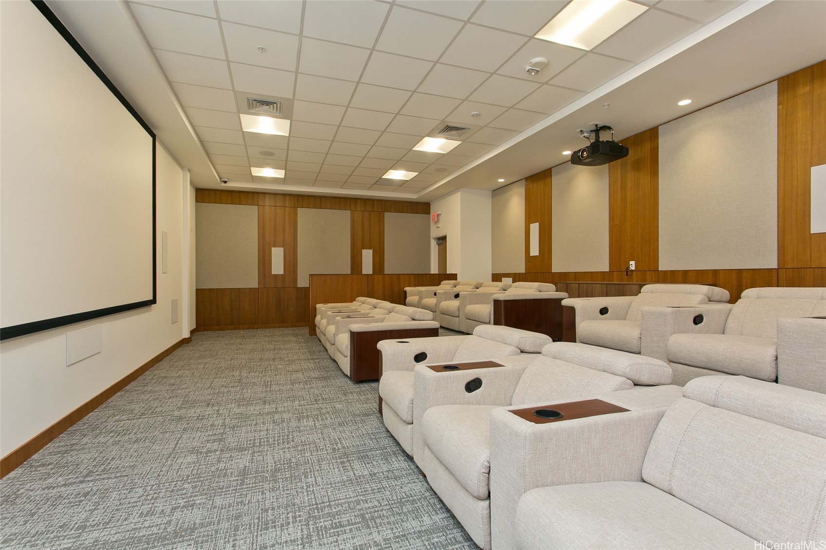 Building theater with rows of upholstered reclining seats facing a large projection screen.