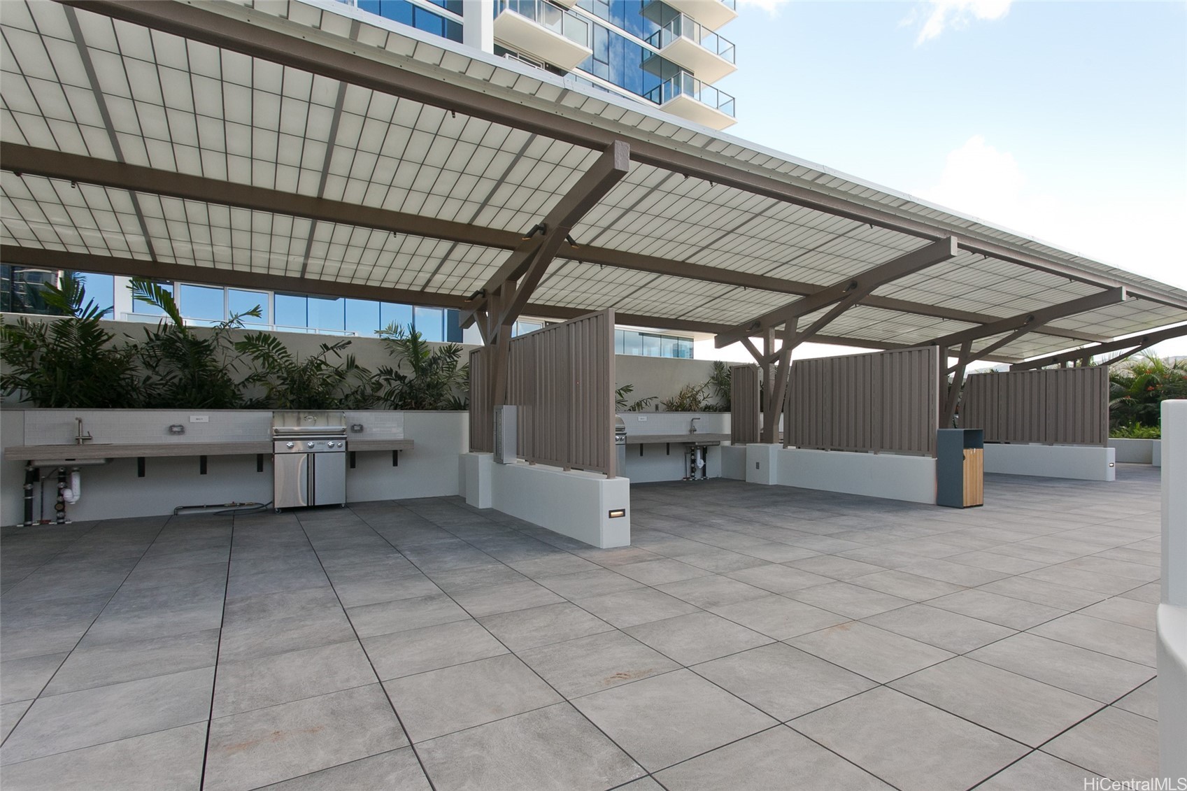 Covered condominium terrace with built-in grills, sinks, and tiled flooring.
