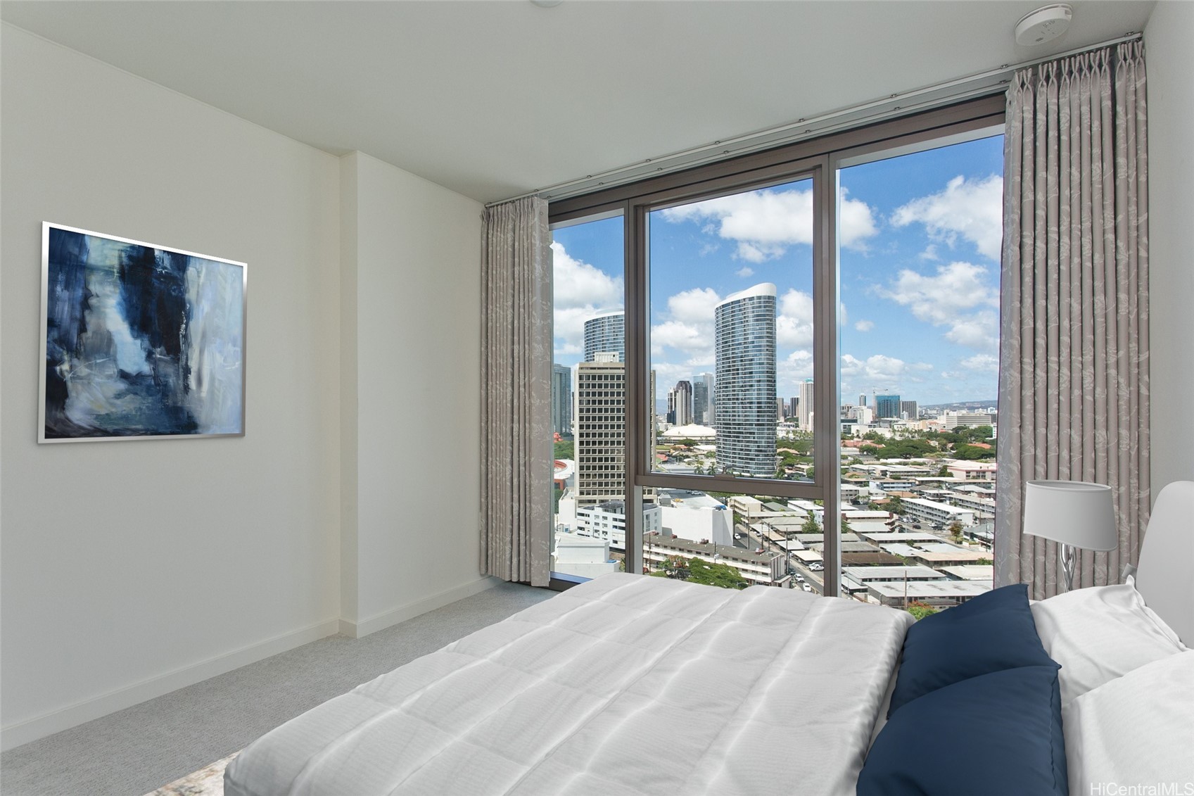 Bedroom with floor-to-ceiling windows overlooking Honolulu’s city skyline.
