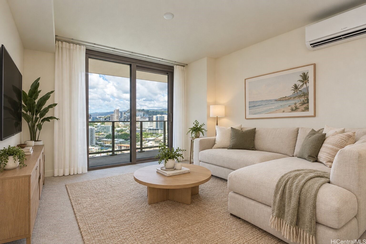 Staged living room with a cream sectional and balcony doors overlooking Honolulu buildings and hills.