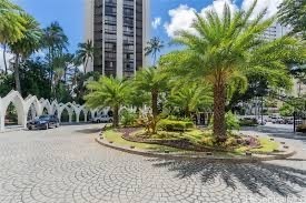 Condominium entrance with a circular paved drive, palm trees, and white arches.