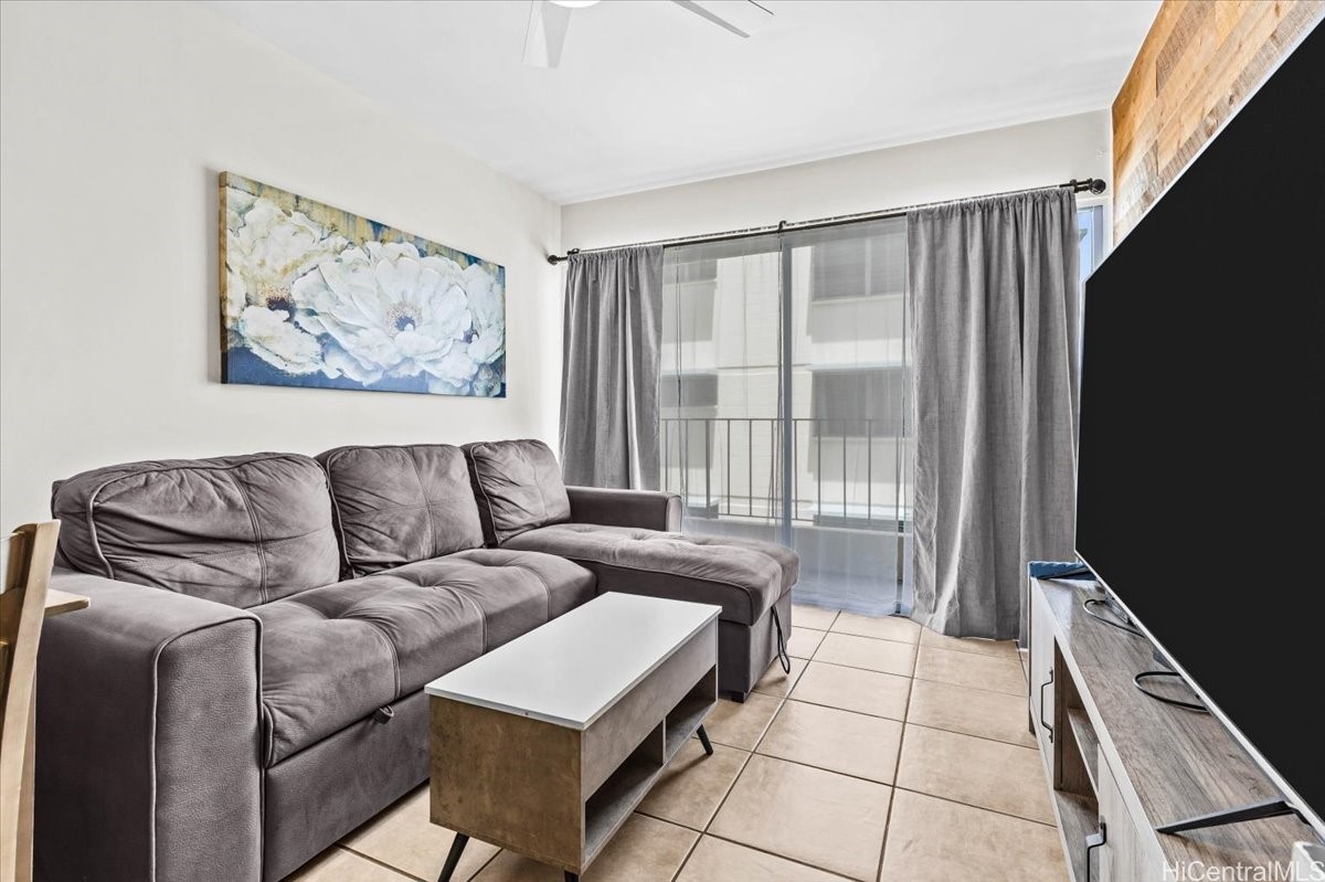 Living room with a gray sectional, white coffee table, and sliding glass doors with gray curtains.