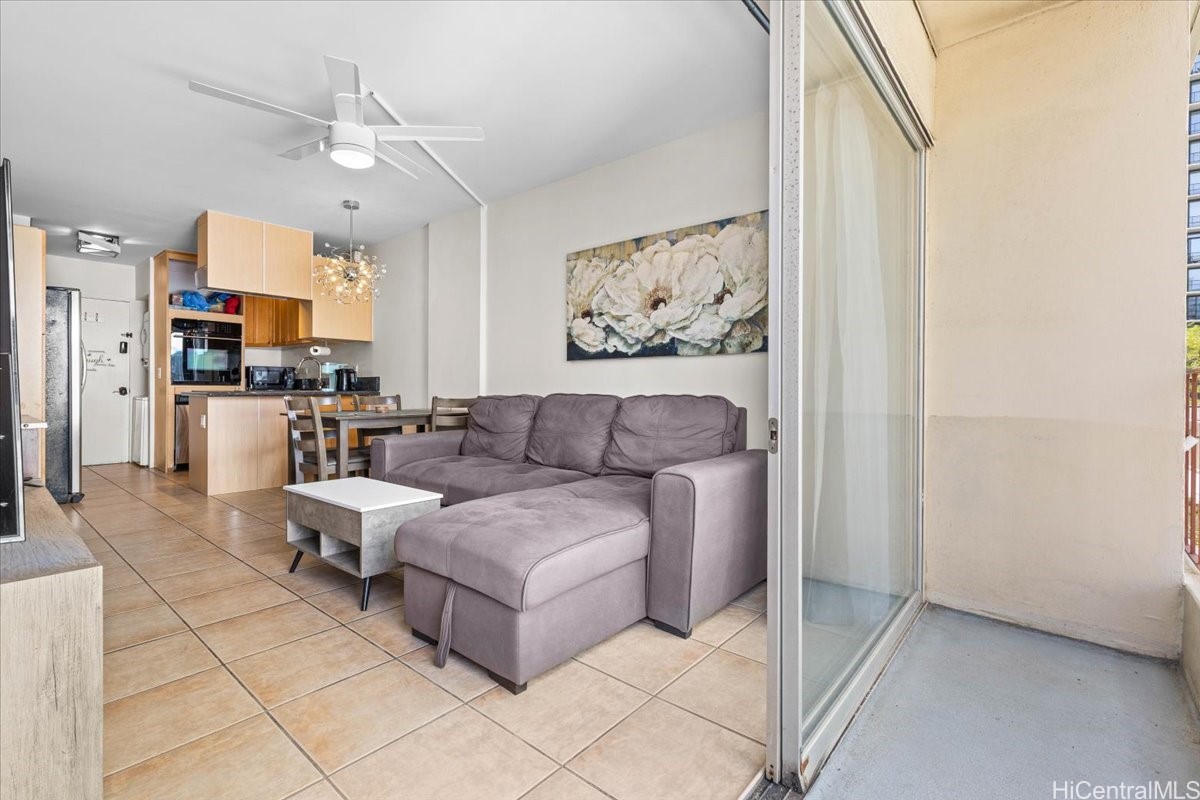 Living room with a gray sectional, open kitchen, and sliding glass doors to a balcony.