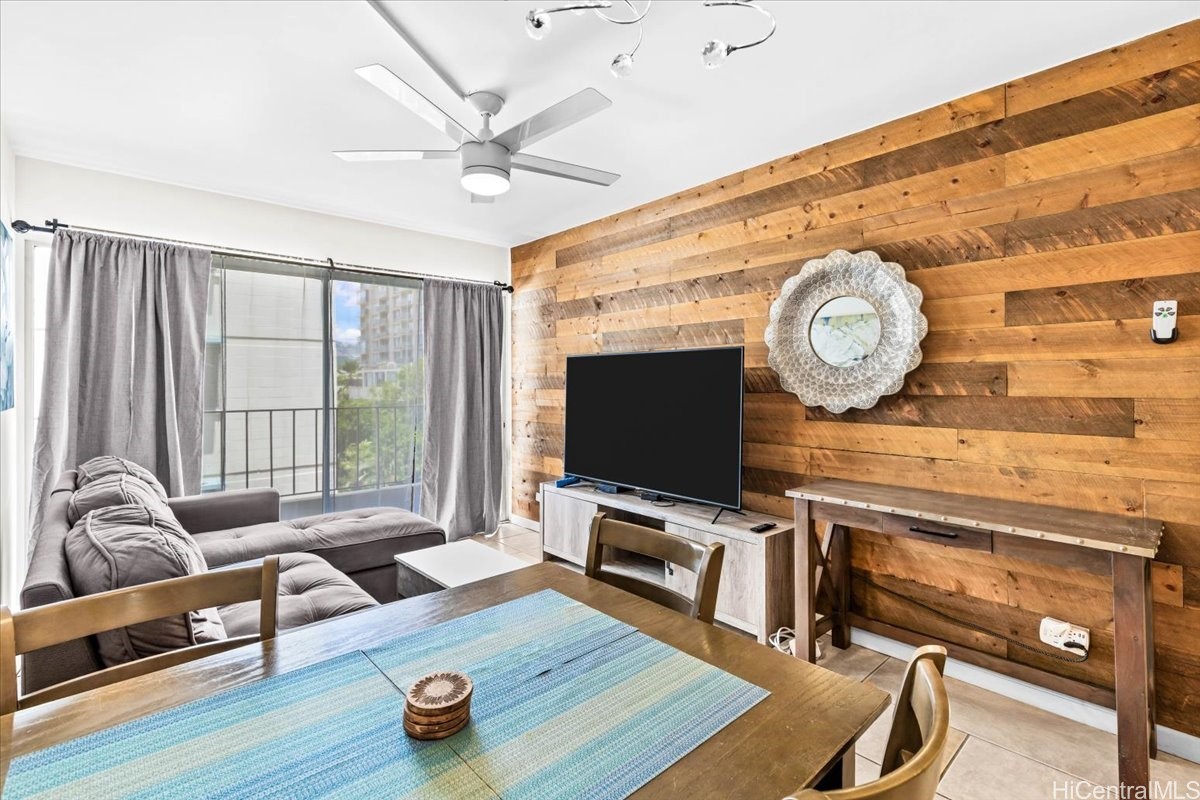 Living and dining area with a gray sectional, sliding glass doors, and a reclaimed-wood accent wall.