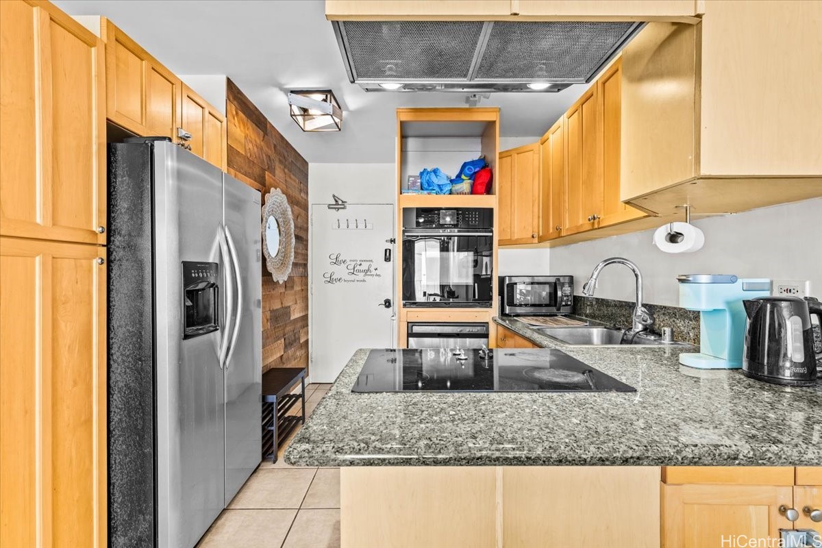 Kitchen with honey-colored cabinets, granite counters, a glass cooktop, and stainless-steel appliances.