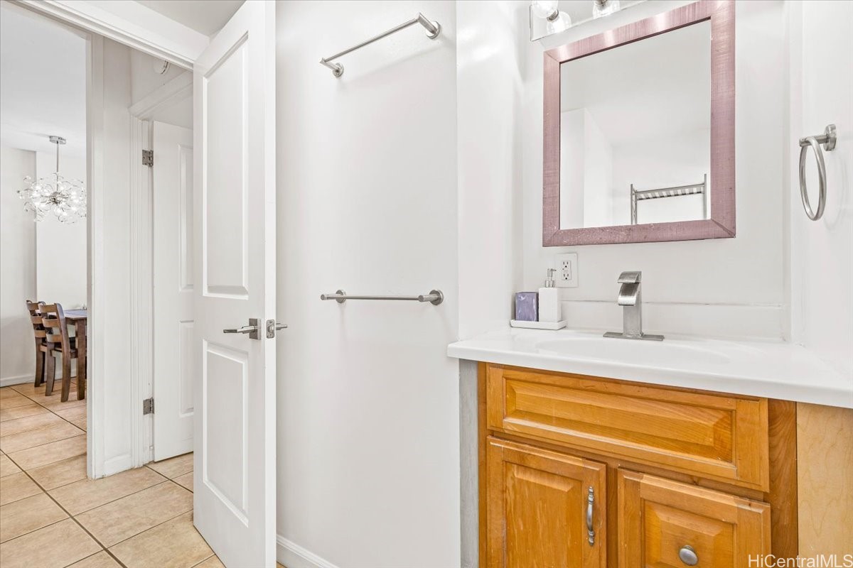 Bathroom vanity with a wood cabinet, white counter, chrome faucet, and framed mirror.