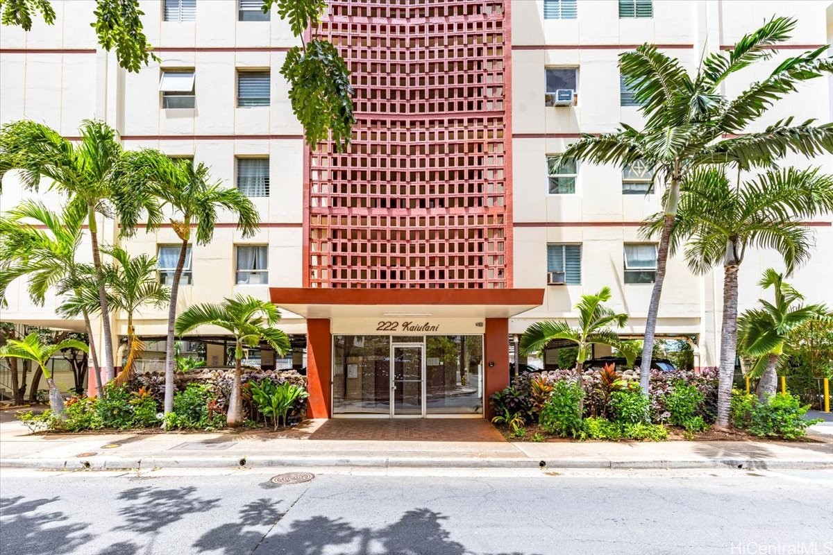 222 Kaiulani condominium entrance with red latticework and tropical palms.