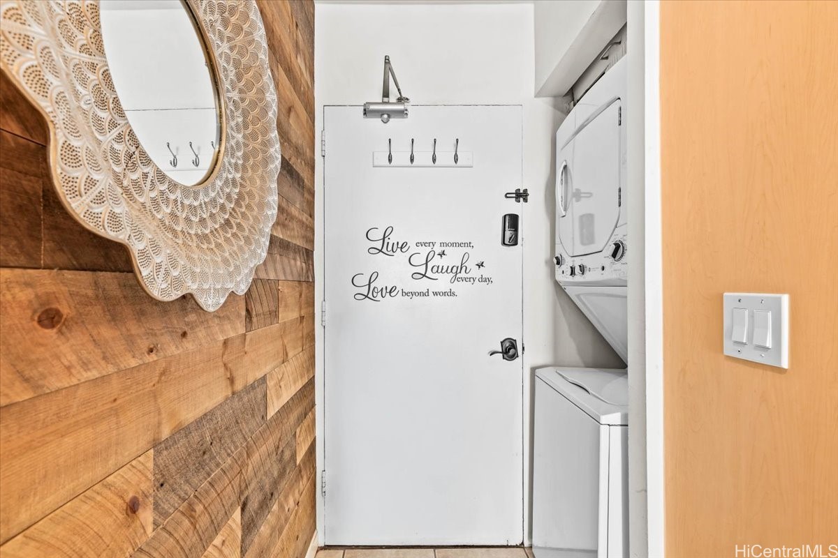 Laundry area with washer and dryer beside a quote-decorated door and wood accent wall.