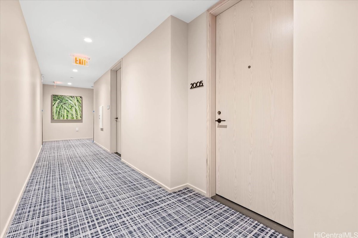 Condo hallway with a patterned carpet and light wood entrance door marked 2005.
