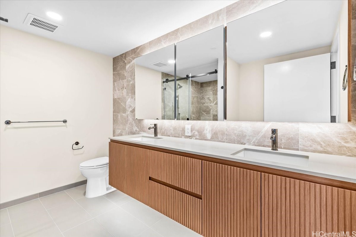 Bathroom with a double-sink vanity, fluted wood cabinetry, and mirrored cabinets.