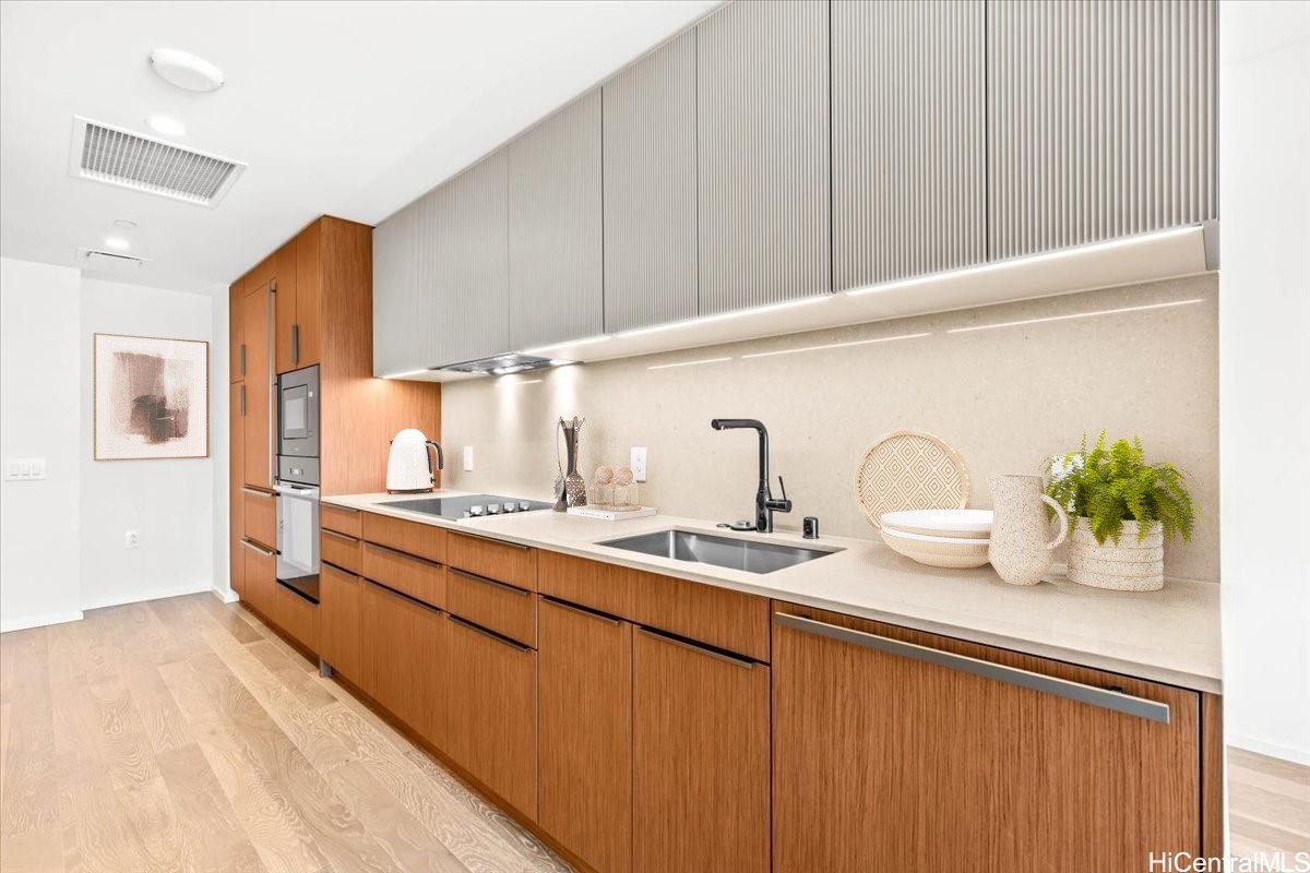 Modern kitchen with walnut cabinetry, ribbed upper cabinets, and a long stone countertop.