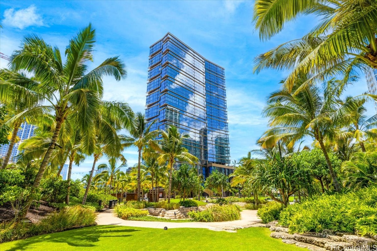 Glass high-rise condominium framed by palm trees above landscaped grounds.