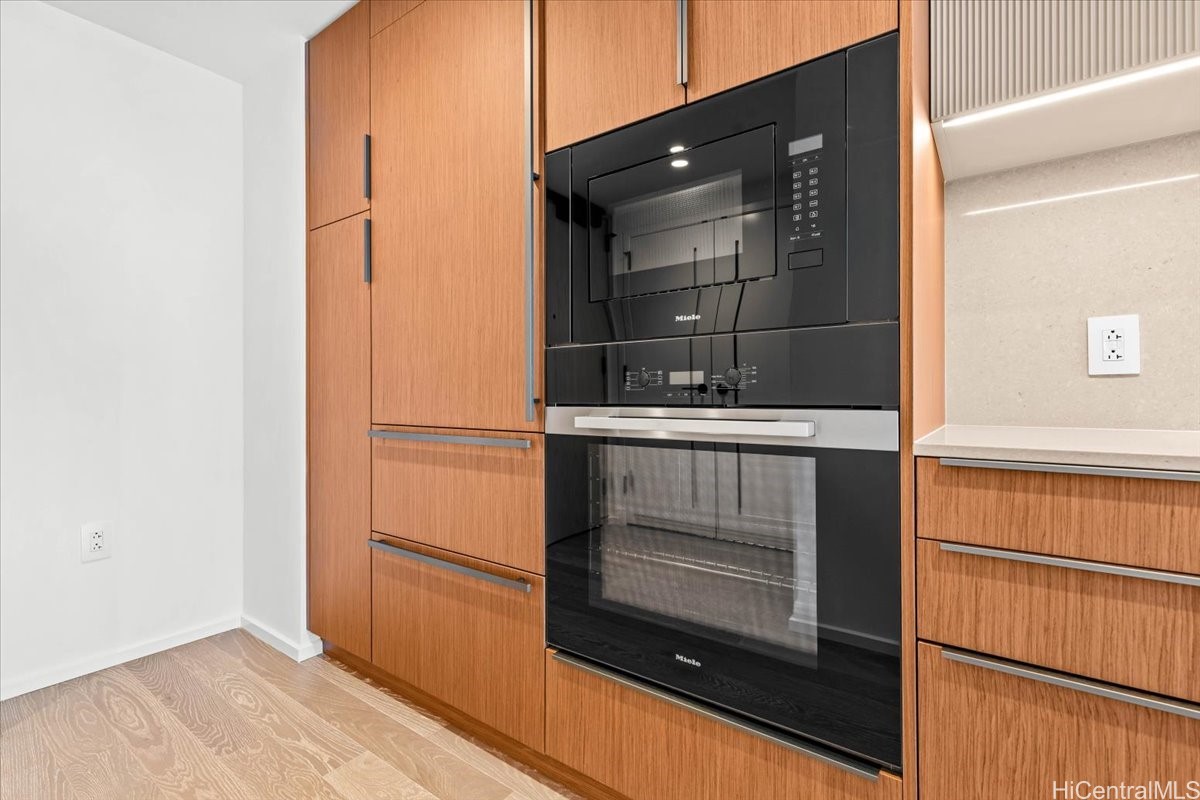 Kitchen with wood cabinetry and a black built-in Miele microwave and oven.