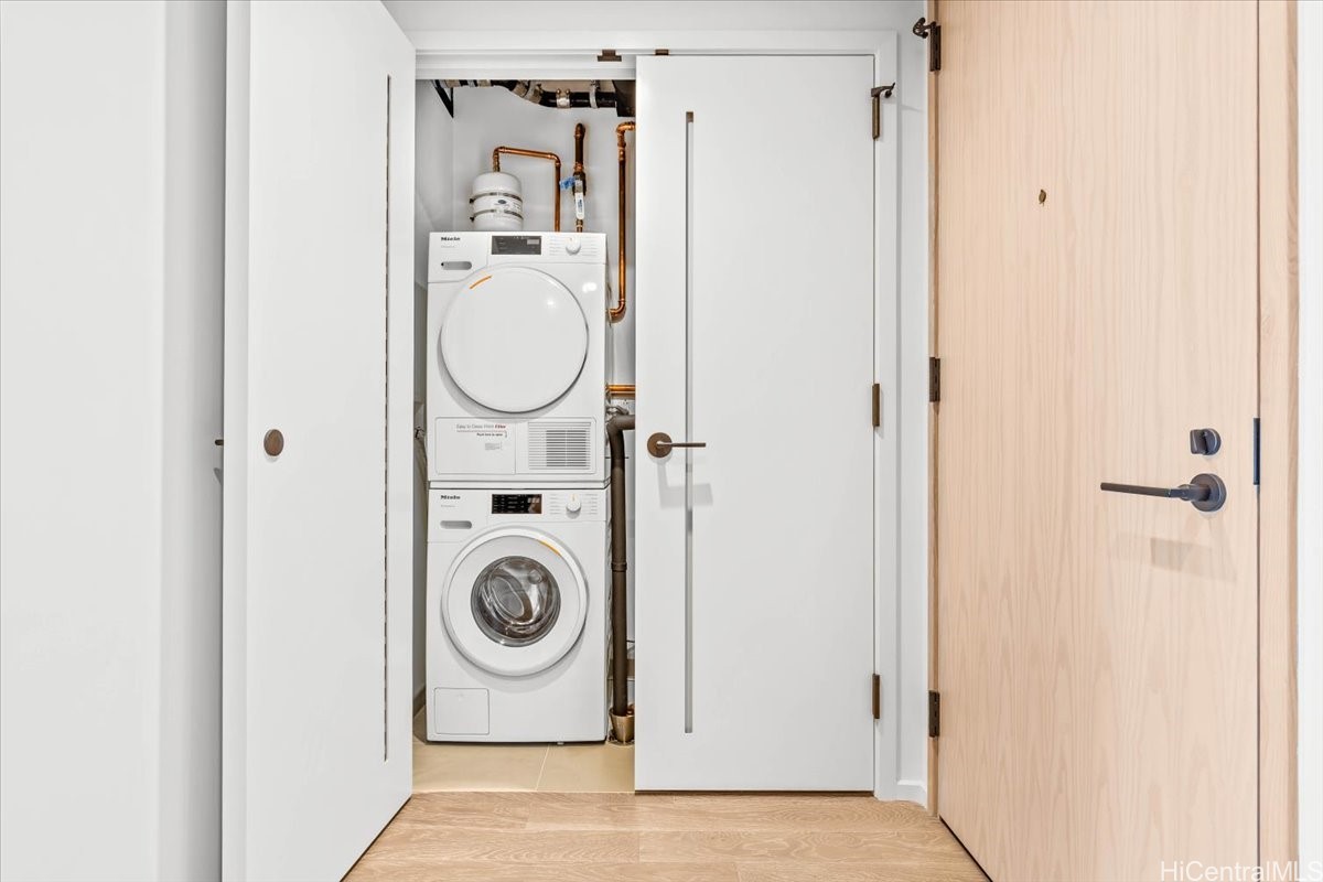 Laundry closet with stacked Miele washer and dryer behind open doors.