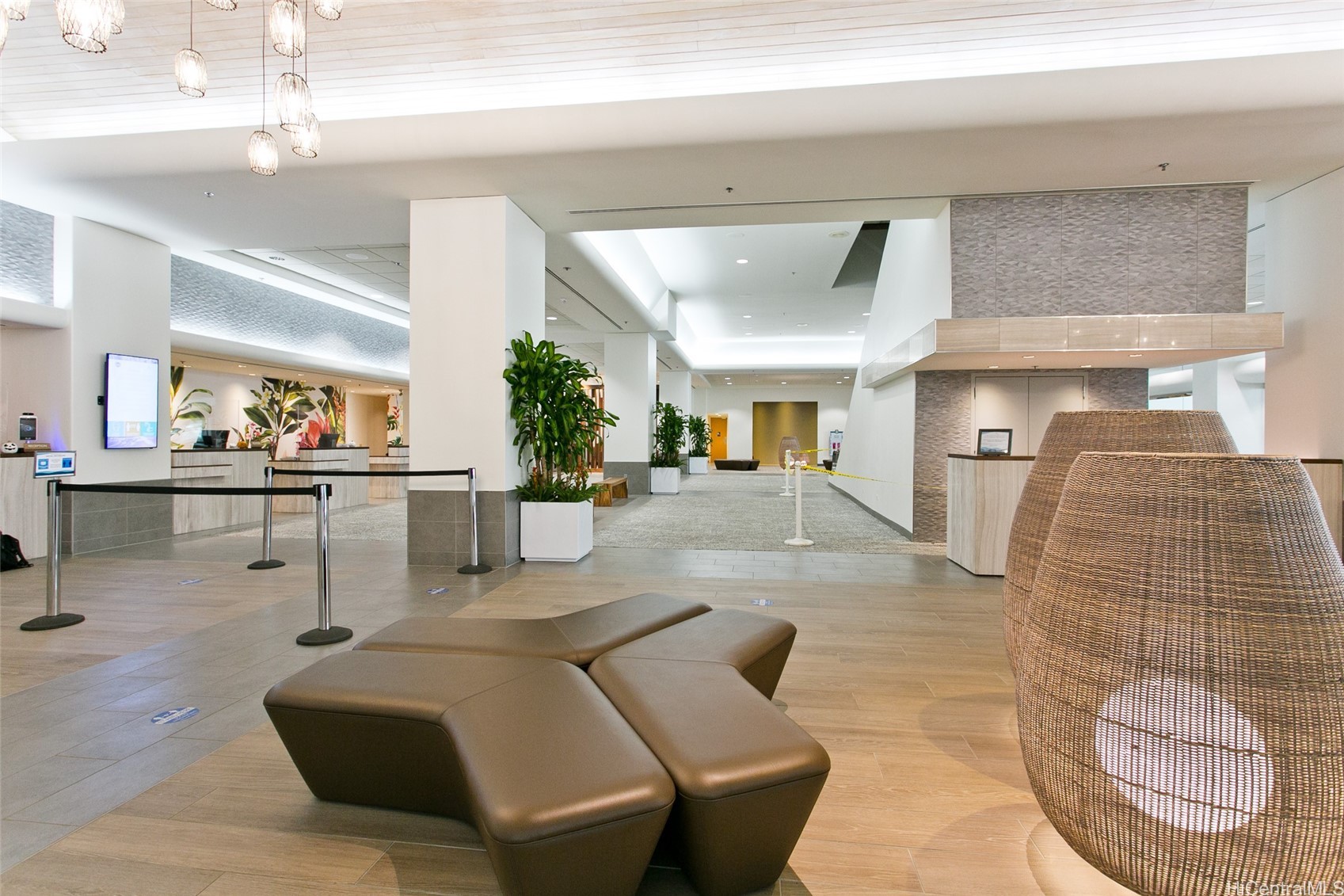 Modern condominium lobby with sculptural brown seating, pendant lights, and a reception desk.