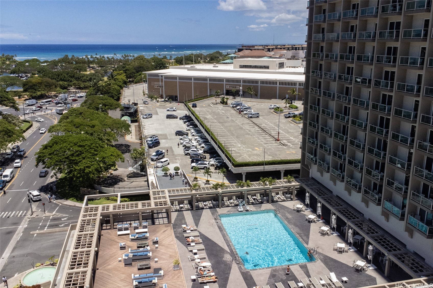 High-rise pool deck with a swimming pool, hot tub, and ocean in the distance.