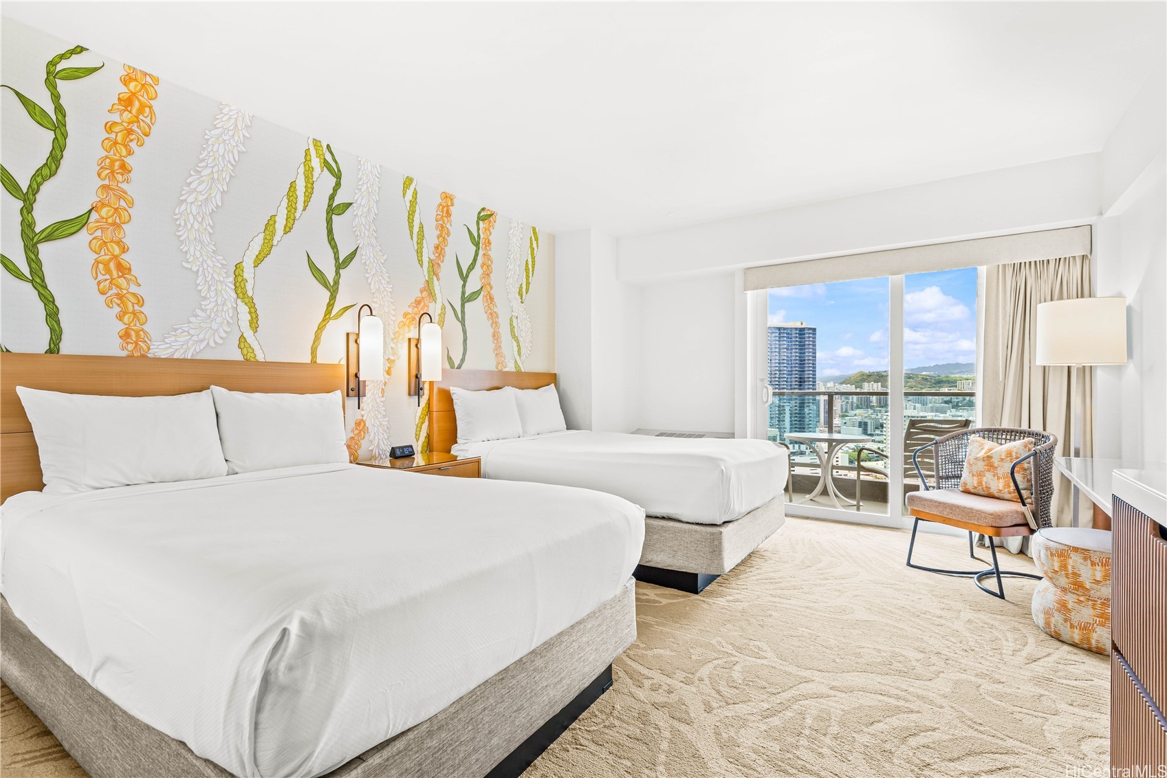 Bedroom with two white beds, a lei-patterned accent wall, and balcony views of Honolulu.