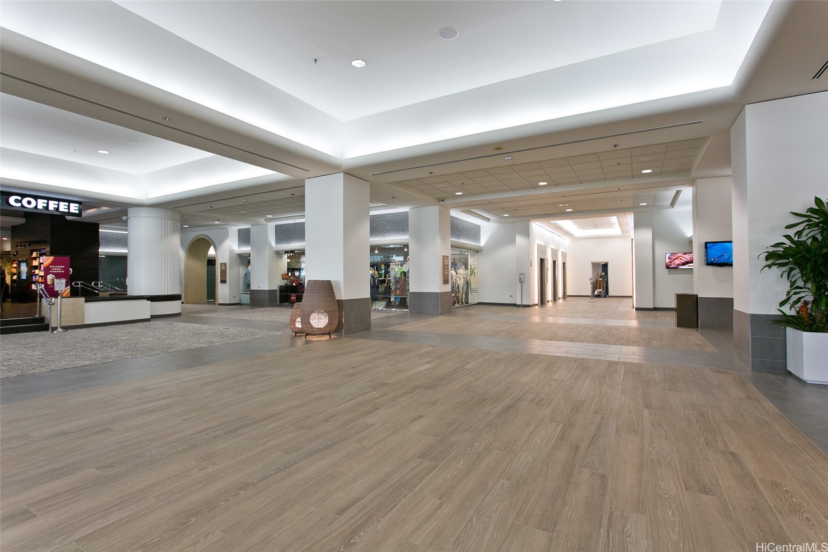 Building lobby with wood-look tile flooring, white columns, and a coffee shop.