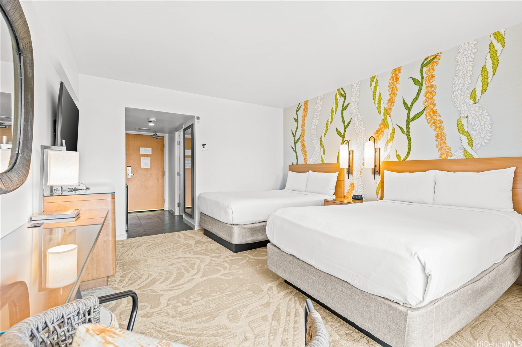 Bedroom with two white beds and a colorful lei-inspired mural behind the headboards.