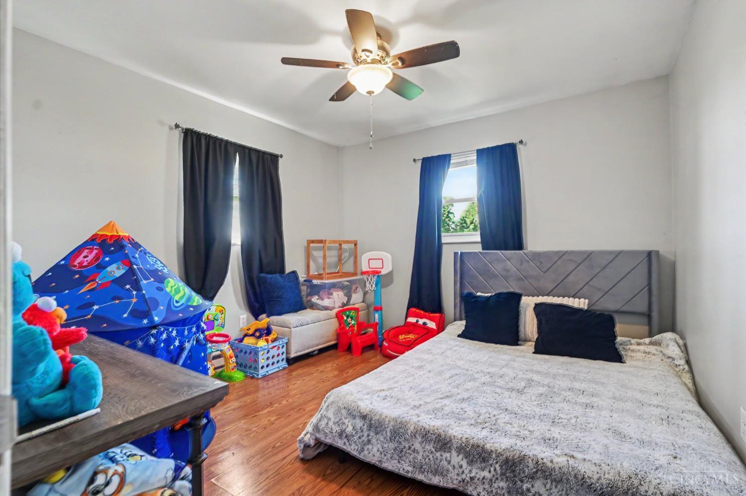 Bedroom with a large bed, wood floors, and a children's play tent and toys.