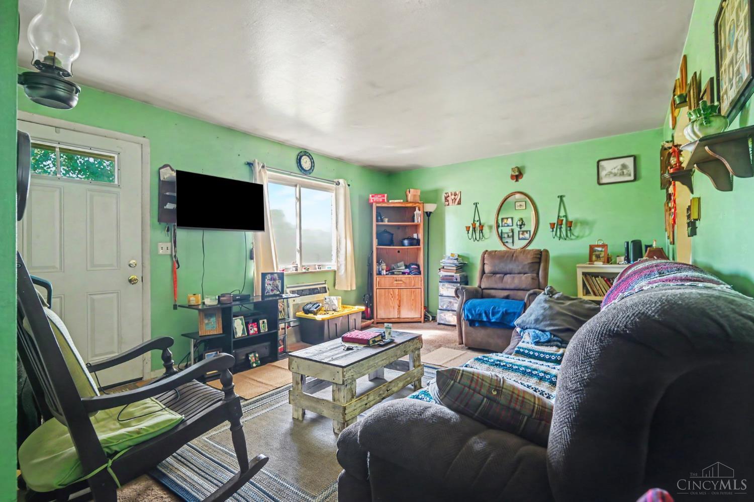 Living room with mint-green walls, a rustic coffee table, recliners, and a television.