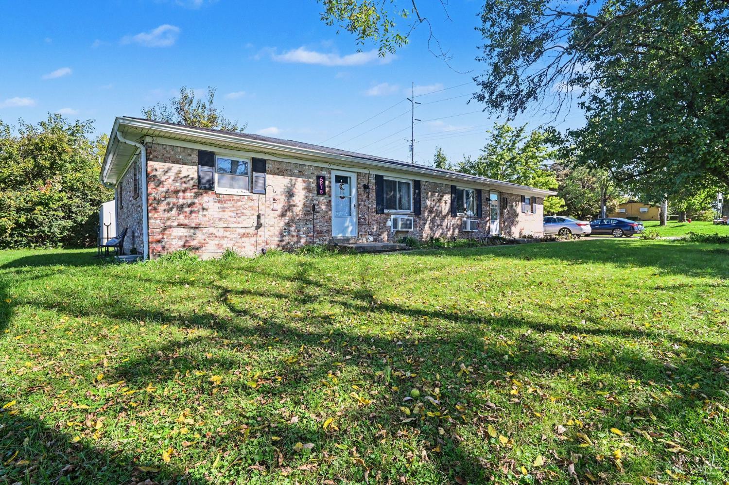 Single-story brick home with a blue front door and a broad grassy yard.