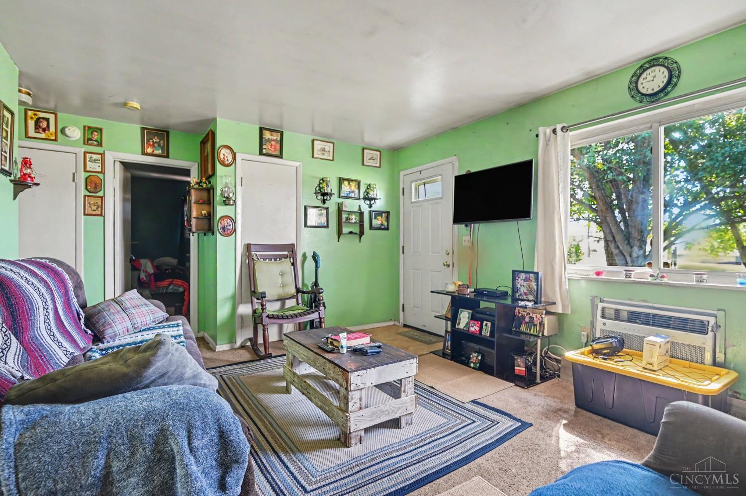 Living room with bright green walls, a rocking chair, rustic coffee table, and large window.