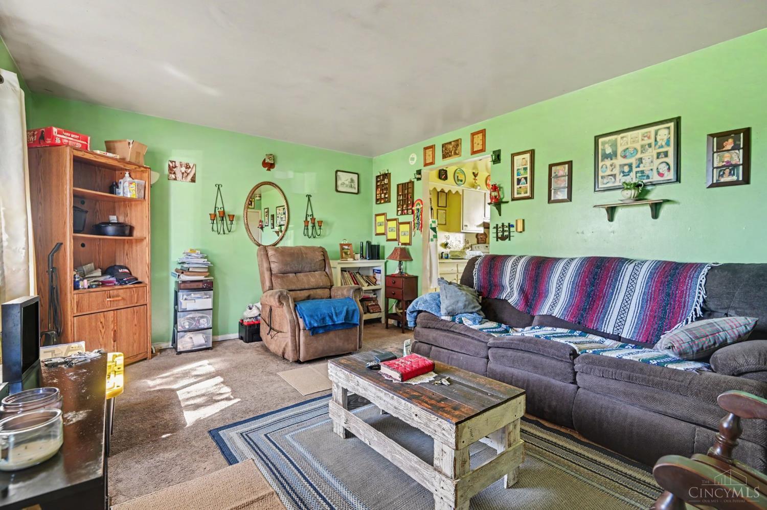 Living room with mint-green walls, a large sectional sofa, and a rustic wooden coffee table.
