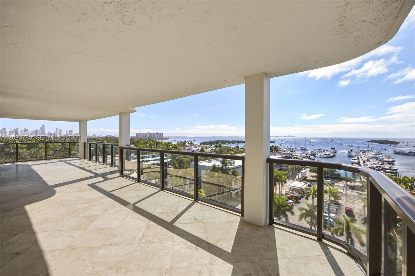 Empty tiled balcony overlooking a marina, bay, and distant city skyline.