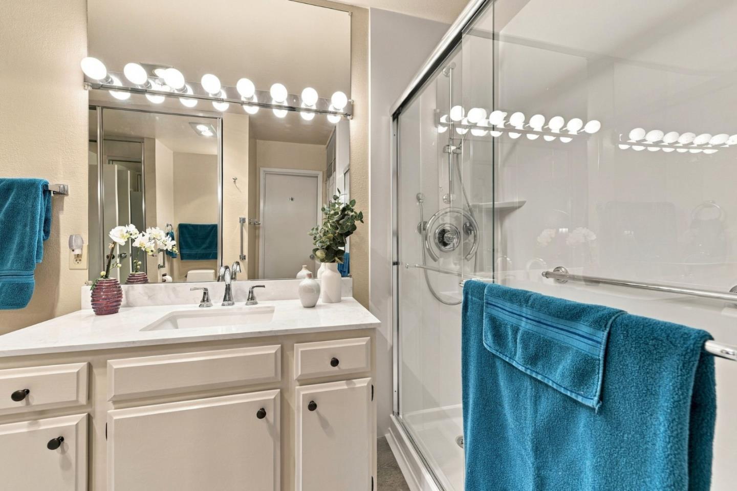 Bathroom with a white vanity and glass-enclosed shower, accented by blue towels.