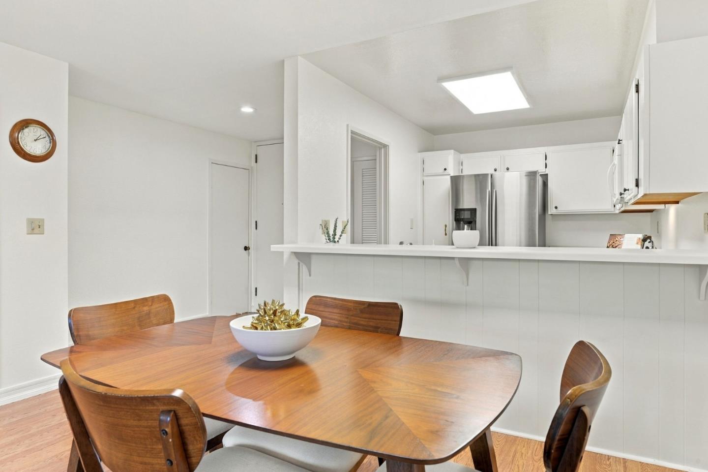 Kitchen and dining area with white cabinets, stainless steel refrigerator, and a wooden dining table.