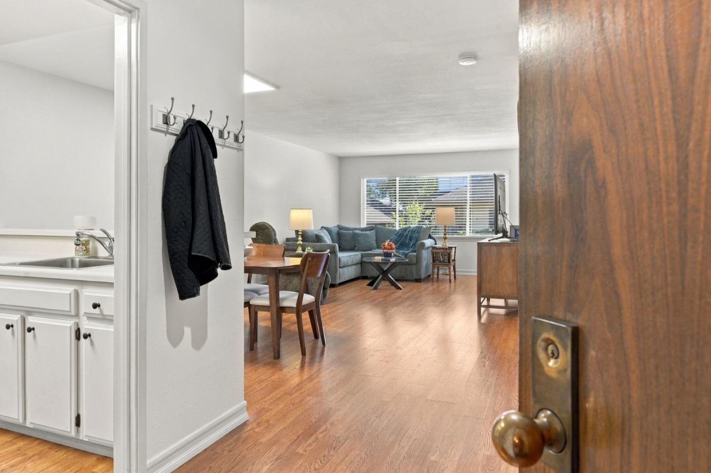 Furnished living and dining area with wood floors, a blue-gray sofa, and a window with blinds.