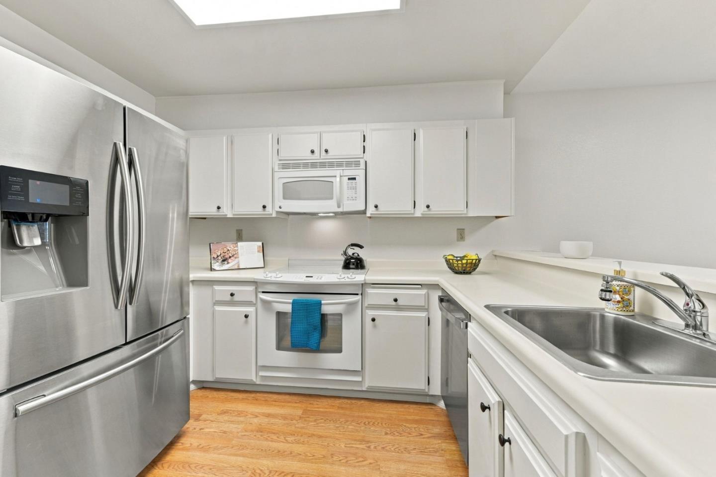 Kitchen with white cabinetry, stainless steel appliances, and hardwood floors.