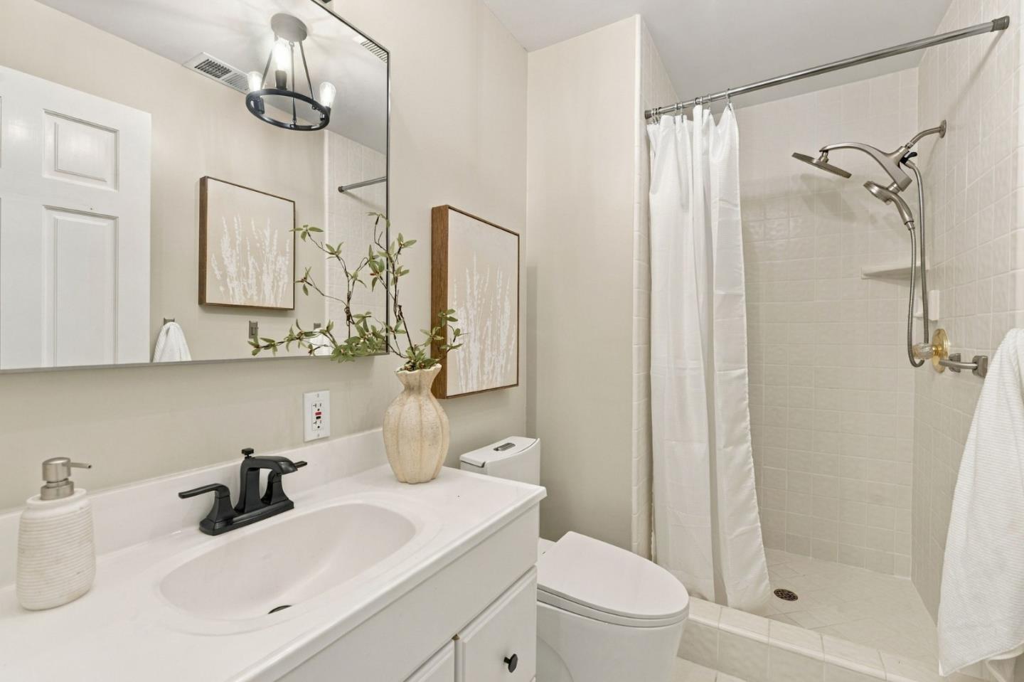 Bathroom with a white vanity and large mirror beside a tiled walk-in shower.